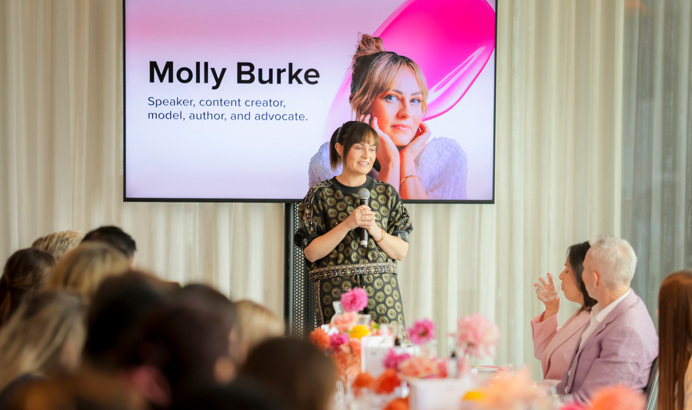 An image of Molly Burke speaking on stage at the Boundless Beauty Summit.