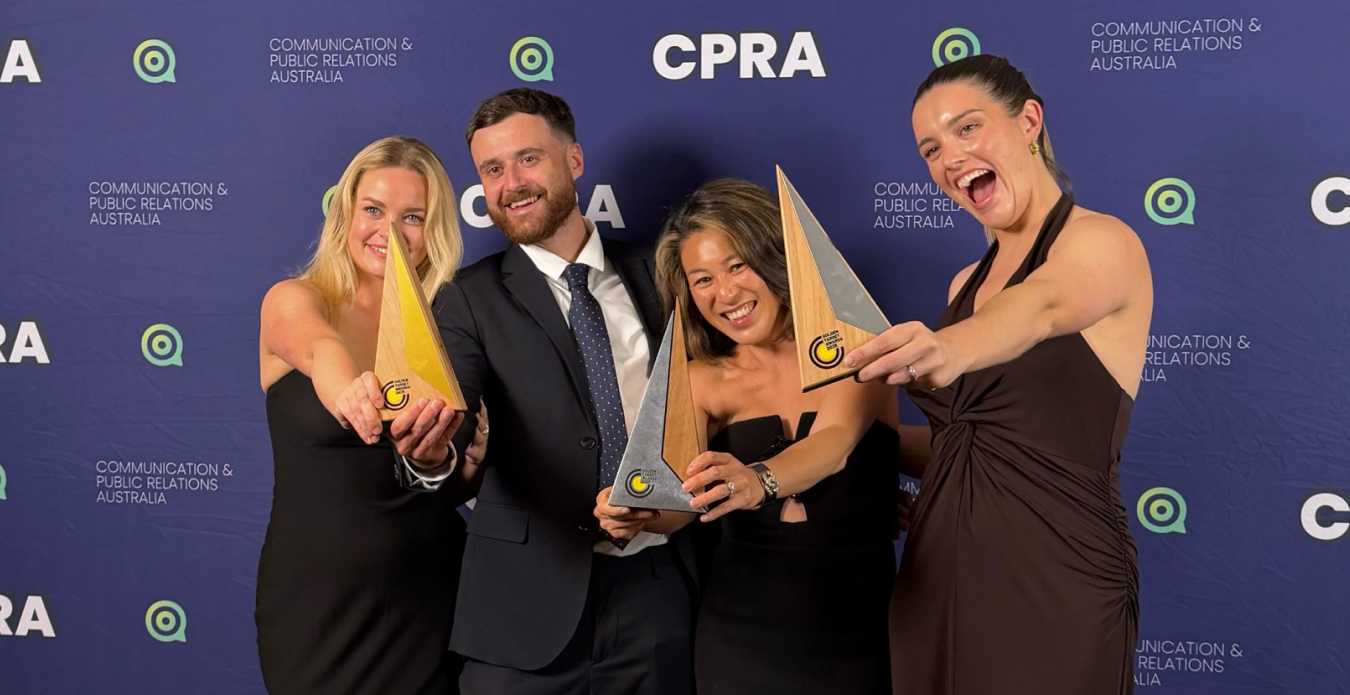 Image of four Keep Left team members at an awards show holding three trophies.
